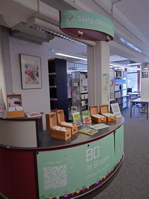 Blick auf die Saatgutbibliothek im Eingangsbereich der Fachbibliothek Technik mit den Saatgutkästen, passenden Büchern und Deko