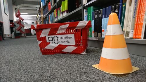 Baustelle in der Bibliothek: ein Pylon vor Bibliotheksregalen