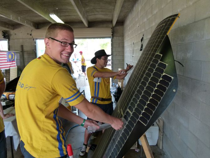 Tim Schlinkmann reinigt zusammen mit Linh Hoang mit Klebeband die Solarzellen