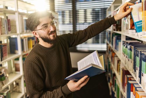 Junger Student in Bibliothek