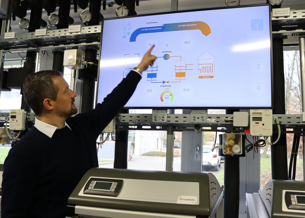 Ein Beispiel für die Sektorenkopplung: Der gewonnene Strom aus erneuerbaren Energien wie Wind und Sonne wird von Wärmepumpen zum Heizen genutzt. Prof. Dr. Rath zeigt auf einen Bildschirm, auf dem ein Beispiel für die Sektorenkopplung zu sehen ist: Der gewonnene Strom aus erneuerbaren Energien wie Wind und Sonne wird von Wärmepumpen zum Heizen genutzt.