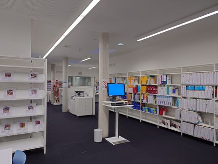 Foto Fachbibliothek Gesundheit: Blick von den Bibliotheksregalen Richtung Theke