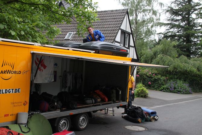 Lars Gebauer und Felix Burmeister verstauen das Gepäck in den Dachboxen des Anhängers