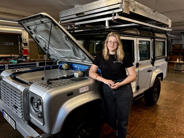 Im SolarCar-Projekt haben Studierende einen Landrover, der verschrottet werden sollte, ausgeräumt und elektrifiziert. Xenia Wiedenmannott steht vor dem umgebauten Landrover.