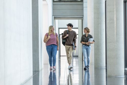 Drei Studierende laufen einen Flur entlang